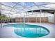 Screened-in pool with a white frame and a pebble walkway with an adjacent retaining wall providing additional privacy at 3114 Jemima Ave, The Villages, FL 32163