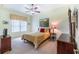 Comfortable bedroom features soft carpet, ceiling fan, stylish decor, and plenty of natural light at 3506 Mulberry Grove Loop, Leesburg, FL 34748