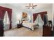 Relaxing main bedroom featuring soft carpet, ceiling fan, accent lamps, and large windows with draperies at 3506 Mulberry Grove Loop, Leesburg, FL 34748