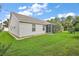 Lush green backyard featuring a well-maintained lawn, landscaping, and a screened-in patio at 1306 De La Garza Pl, The Villages, FL 32162