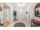 Bright foyer with white tile flooring, decorative plant, and a wicker table to give an inviting view when entering the home at 1306 De La Garza Pl, The Villages, FL 32162