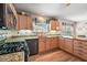 The kitchen features granite counters, appliances, a gas cooktop, wood cabinets, and backsplash for a traditional design at 1306 De La Garza Pl, The Villages, FL 32162