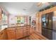 The kitchen island features granite counters, and a stainless steel refrigerator in a kitchen with a dining area near the windows at 1306 De La Garza Pl, The Villages, FL 32162