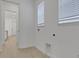 All-white laundry room with a hookup for a dryer and two large windows at 6521 Daypack Ln, St Cloud, FL 34771
