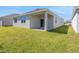 Back of a home with a covered patio area and a sliding glass door, surrounded by a green lawn at 191 Bottle Brush Dr, Haines City, FL 33844