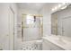 Bright bathroom features a shower-tub combo with gold trim, white cabinets, and black and white tiled floors at 5008 Greenbriar Trl, Mount Dora, FL 32757