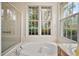 Bright bathroom featuring a garden tub, glass enclosed shower and large windows at 5008 Greenbriar Trl, Mount Dora, FL 32757