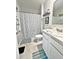 This bathroom features a patterned shower curtain and blue accent rugs at 1771 Henin Cir, Tavares, FL 32778