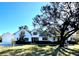 Charming white two-story home with lush lawn and mature shade tree on a sunny day at 26012 Splendid Meadow Ct, Astatula, FL 34705