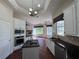 Well-lit kitchen features stainless appliances, white cabinetry, island sink, dark counters, open to living space at 26012 Splendid Meadow Ct, Astatula, FL 34705