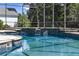 Close up of a sparkling in-ground pool inside of a screened enclosure and mature trees beyond at 26012 Splendid Meadow Ct, Astatula, FL 34705
