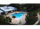 Aerial view of a sparkling blue pool and spa surrounded by lush landscaping and outdoor seating at 10643 Grand Oaks Blvd, Oxford, FL 34484