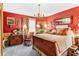 Charming bedroom with antique wooden bed, red walls, and floral decor at 1785 Maine Ct, Tavares, FL 32778