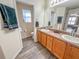 Double vanity bathroom with wood cabinets and a shower at 1101 Blythe Way, The Villages, FL 32162