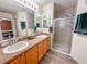 Double vanity bathroom with wood cabinets and a shower at 1101 Blythe Way, The Villages, FL 32162