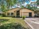 Tan house with carport, two-car garage, and landscaped lawn at 28432 Tammi Dr, Tavares, FL 32778