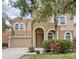Two-story home featuring a clay tile roof, arched entry, two-car garage, and mature landscaping at 436 Orange Cosmos Blvd, Davenport, FL 33837