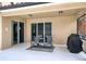Relax on this covered patio with chairs, a small table, grill, and sliding glass doors at 436 Orange Cosmos Blvd, Davenport, FL 33837