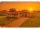 Inviting single-story home featuring a well-manicured lawn, brick driveway, and beautiful landscaping at sunset at 5159 Greens Dr, Lady Lake, FL 32159