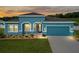 Beautiful teal home with a two-car garage and well-manicured lawn at 6042 Claystone Way, Mount Dora, FL 32757