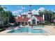 Community pool surrounded by lawn chairs and tropical landscaping on a sunny day with residents swimming at 11508 Westwood Blvd # 328, Orlando, FL 32821