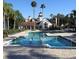 Community pool with palm trees and landscaped greenery on a sunny day with lounge chairs nearby at 11508 Westwood Blvd # 328, Orlando, FL 32821