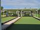 Outdoor bocce ball court featuring artificial turf, shade structures with benches, and pristine landscaping at 5206 Fantasy Way, Leesburg, FL 34748