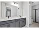 Bathroom with double sinks, gray cabinets, black fixtures, and walk in shower at 6224 Trailblaze Bnd, Saint Cloud, FL 34771