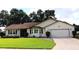 Single story house with a two-car garage, nicely landscaped lawn, and brick paved driveway at 6410 Tildon Ct, Leesburg, FL 34748