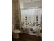 Bright bathroom with flower curtain, wood-style floor, decorative shelving and efficient layout at 104 Turtle Run, Umatilla, FL 32784