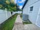 Side yard featuring white fence, green grass, walkway, air conditioner and storage shed at 1415 Harnden W Rd, Port Orange, FL 32129