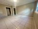 Bedroom with neutral colored walls and floor tiles, featuring a closet and two doorways at 1415 Harnden W Rd, Port Orange, FL 32129