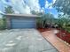 Charming home exterior with a blue garage door, brick accents, and lush landscaping leading to the front porch at 1415 Harnden W Rd, Port Orange, FL 32129