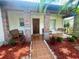 Inviting front porch with brick columns, seating, and a charming swing, enhanced by colorful landscaping at 1415 Harnden W Rd, Port Orange, FL 32129