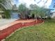 Well-manicured front yard featuring palm trees, a tiled walkway, and decorative mulch beds, enhancing curb appeal at 1415 Harnden W Rd, Port Orange, FL 32129