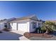 Two-car garage, light-colored siding, and a palm tree at 1750 Kingfisher Ct, The Villages, FL 32162