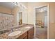 Bathroom with granite double vanity, mirror, and doorway to carpeted bedroom at 4947 Ne 124Th Rd, Oxford, FL 34484