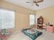 Neutral bedroom with ceiling fan and window with sheer floral print curtains at 4947 Ne 124Th Rd, Oxford, FL 34484