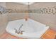Close-up of a white soaking tub surrounded by neutral-toned tiles with mosaic accents at 2602 Tryon Pl, Windermere, FL 34786