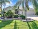 House exterior showcasing landscaping, a large lawn, and palm trees at 2673 Beckett Run, The Villages, FL 32162