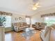 Bright living room featuring hardwood floors,reclining sofas, and a ceiling fan at 2673 Beckett Run, The Villages, FL 32162