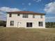 Rear exterior of the tan home featuring a large backyard, sliding glass doors, and a concrete patio at 18744 Sabal St, Orlando, FL 32833