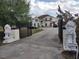 View of the property from the gate featuring lion statues, a large driveway, mature trees, and the home at 18744 Sabal St, Orlando, FL 32833