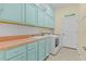 Laundry room with light teal cabinets and orange countertop at 25304 Forest Oak Ct, Leesburg, FL 34748