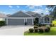 Three-car garage, gray exterior and manicured lawn at 768 Bradford Loop, The Villages, FL 32163