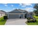 Three-car garage, gray exterior and manicured lawn at 768 Bradford Loop, The Villages, FL 32163