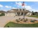 Traditional home with a three-car garage, dormer windows, a covered porch, and an American flag at 4049 Nostalgia Ter, The Villages, FL 32163