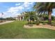 Well-manicured front yard featuring lush green grass, palm trees, and colorful landscaping around the base of the trees at 4049 Nostalgia Ter, The Villages, FL 32163