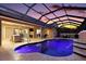 A luxurious screened-in pool illuminated at dusk, with a waterfall feature and outdoor kitchen in view at 4049 Nostalgia Ter, The Villages, FL 32163