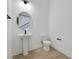 Modern powder room featuring a pedestal sink, toilet, and an oval mirror at 6608 Quest St, St Cloud, FL 34771
